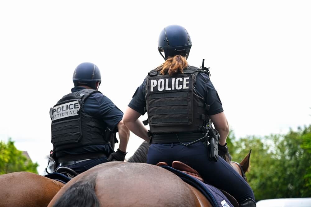 Deux policiers à cheval de la Police Nationale, vus de dos.