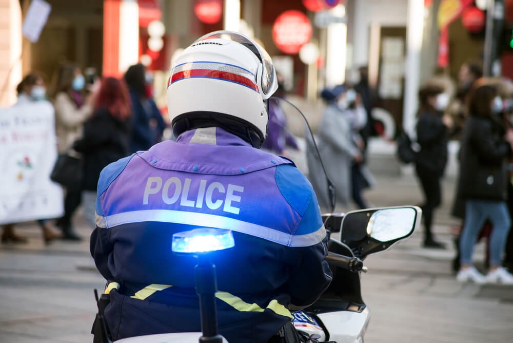 Motard de la police au milieu de personnes avec des masques.