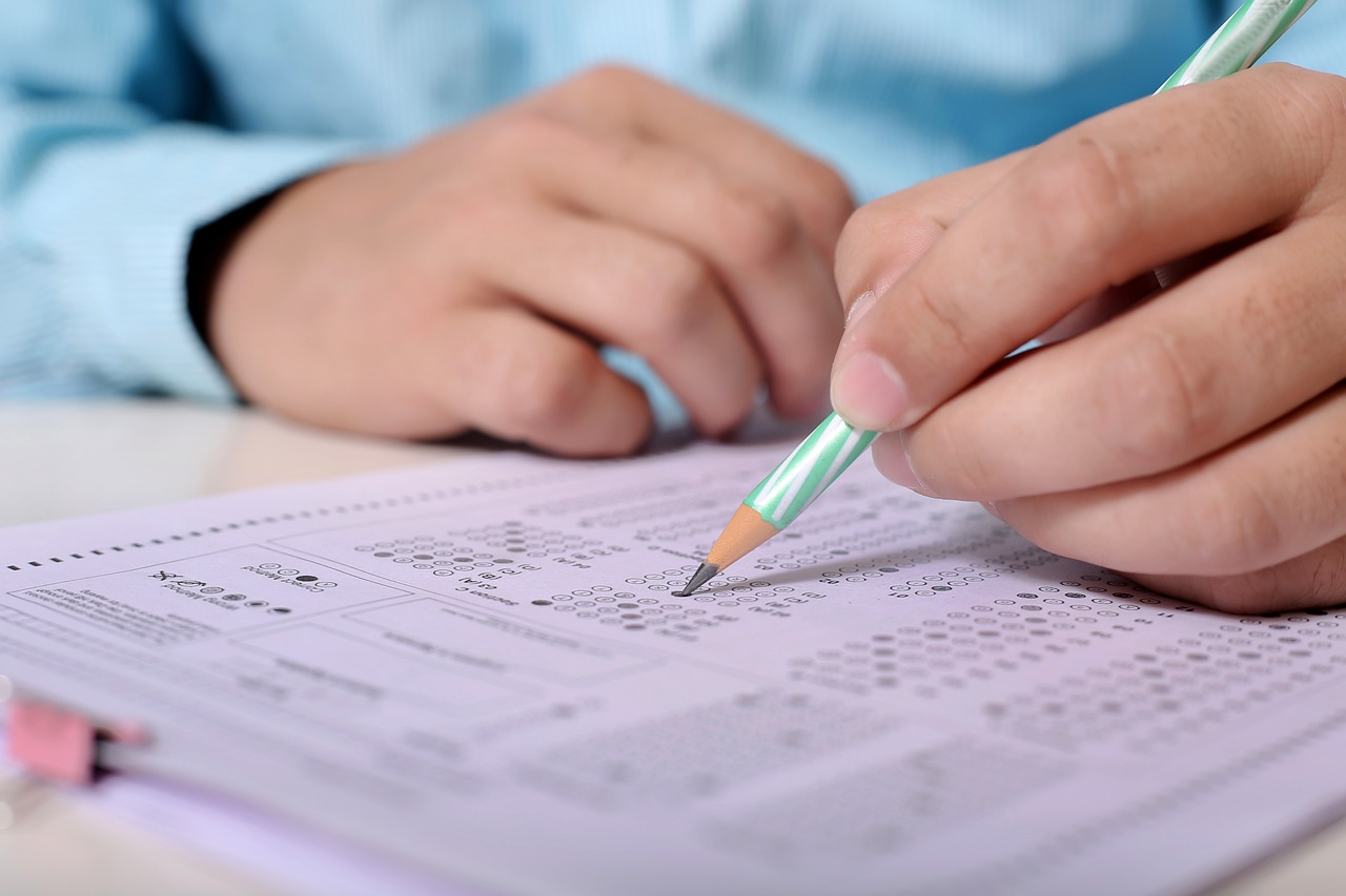 Personne remplissant un questionnaire à choix multiples avec un crayon, focus sur les mains et le questionnaire.