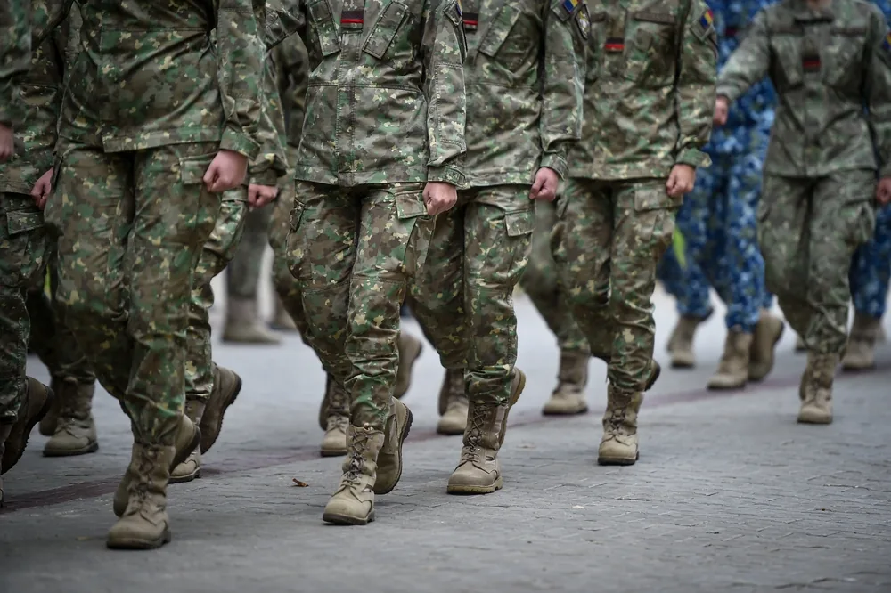 Candidats en treillis marchant au pas dans la cour d'une caserne d'un centre de sélection militaire.
