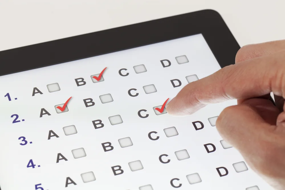 Main sélectionnant une réponse sur un test d'anglais QCM numérique pour évaluer le niveau de langue.