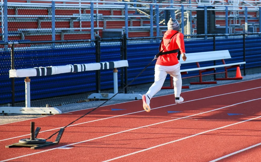 Athlète en plein effort de fractionné sur piste d'athlétisme, représentant un entraînement VMA.