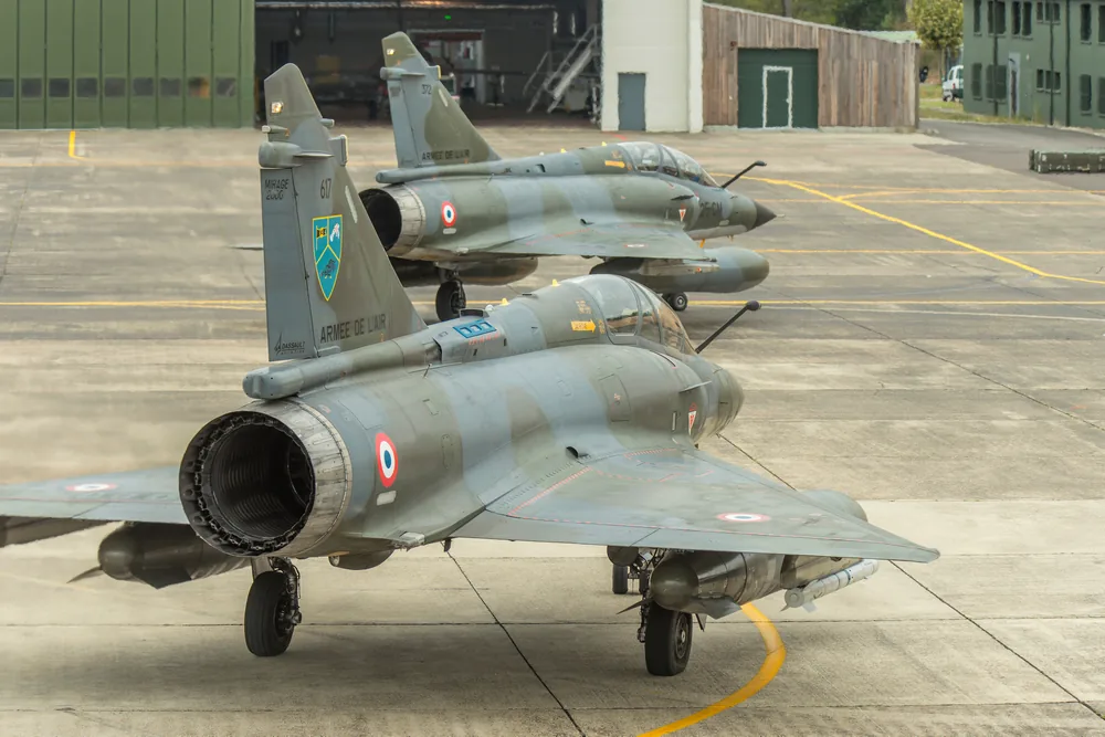 Base aérienne militaire avec piste d'atterrissage et avions de chasse en formation.