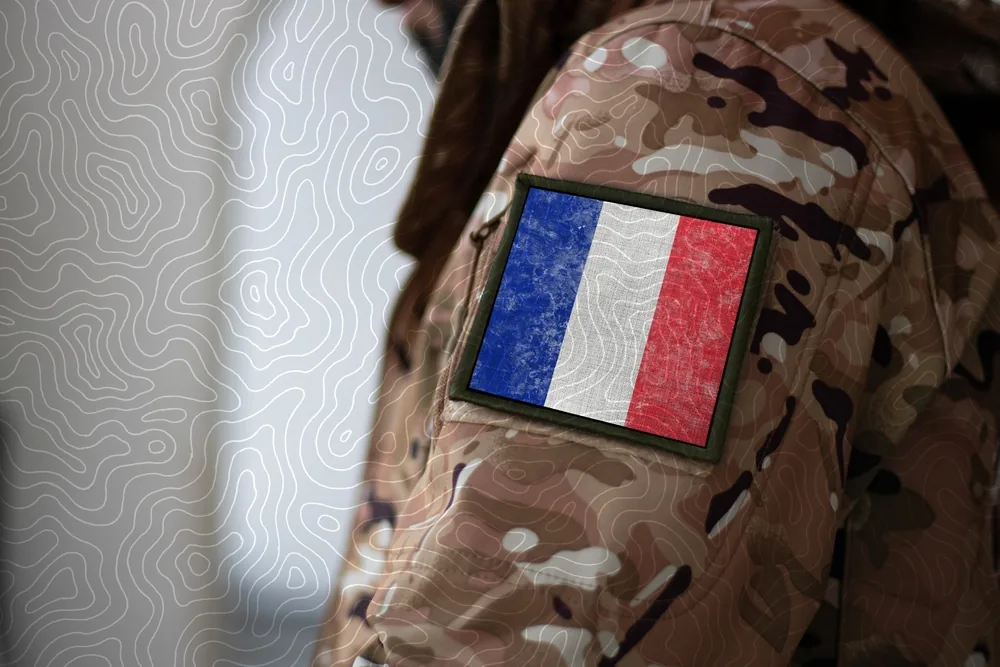 Drapeau tricolore français flottant devant une caserne, symbole d'engagement militaire.