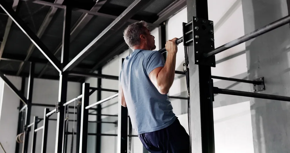 Candidat en tenue de sport effectuant des tractions à la barre fixe lors d'un test physique militaire