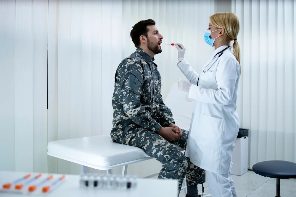 Militaire en uniforme passant un examen médical auprès d'un médecin militaire dans un centre de sélection.