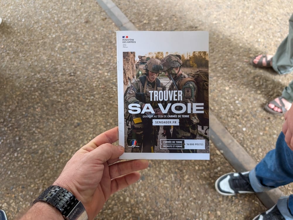 Main tenant une brochure "Trouver sa voie" de l'Armée de terre, illustrant la démarche de recrutement militaire.