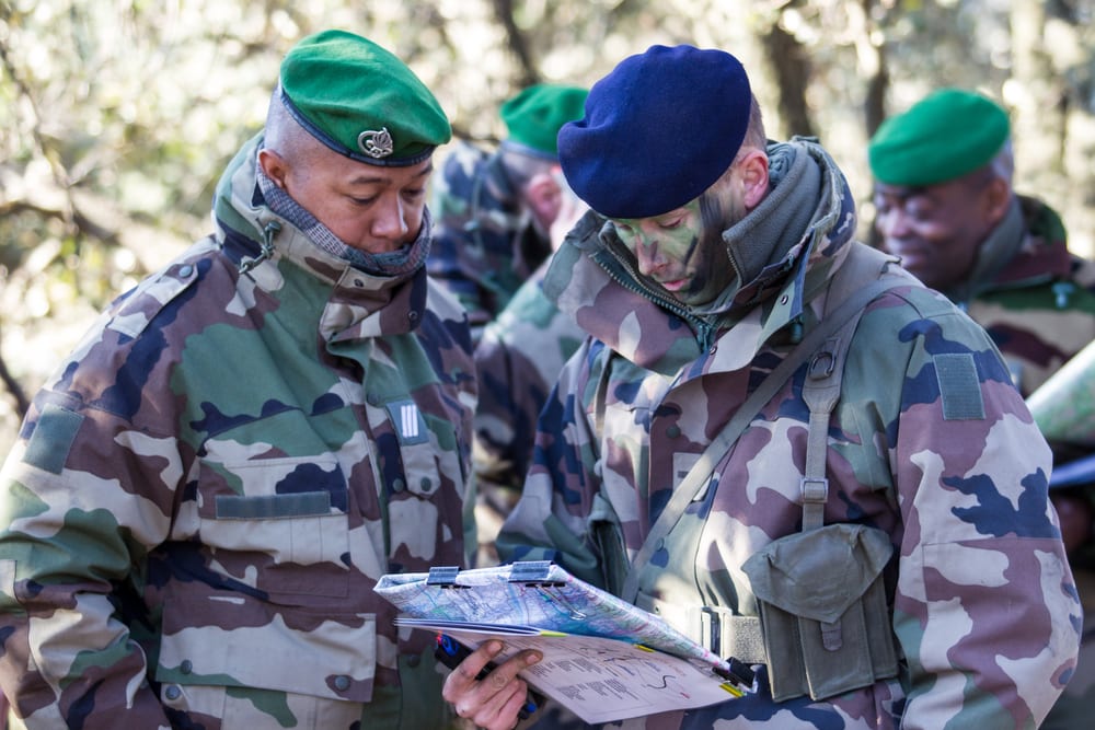 Un officier et un candidat en tenue de combat échangent lors d'un entretien de recrutement sur le terrain.