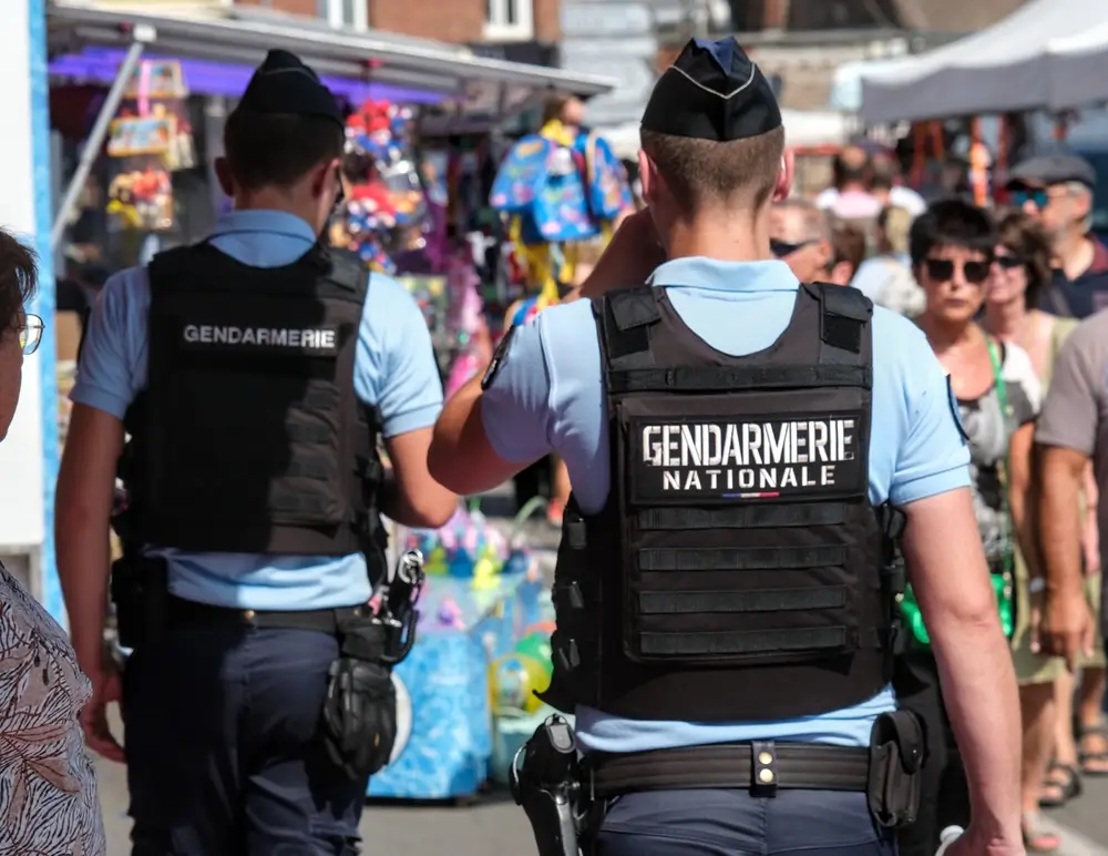 Deux gendarmes français vus de dos en polo bleu, calot et gilet tactique marqué Gendarmerie nationale