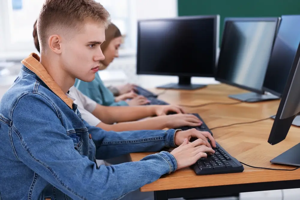 Candidats alignés devant des écrans d'ordinateur lors d'un test informatisé en salle d'examen