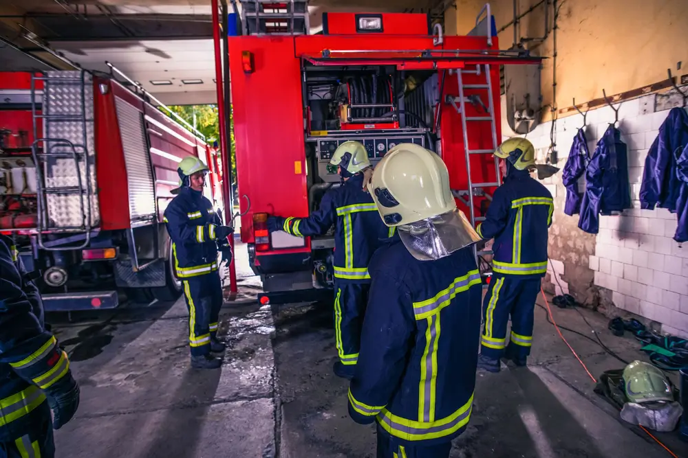 Sapeurs-pompiers professionnels en tenue d'intervention et casque F1 vérifiant le matériel d'un fourgon en caserne